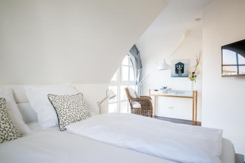 a white bedroom with a bed and a window at Ferienhaus Schilfrohrsaenger 45 in Fuhlendorf