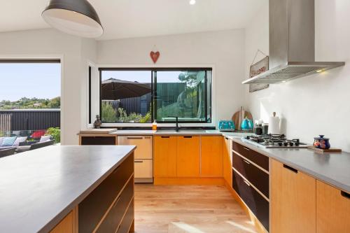 a kitchen with orange cabinets and a large window at R and R at Robertson - Raglan Holiday Home in Raglan