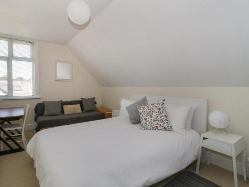 a bedroom with a white bed and a couch at 20 Ulwell Road in Swanage