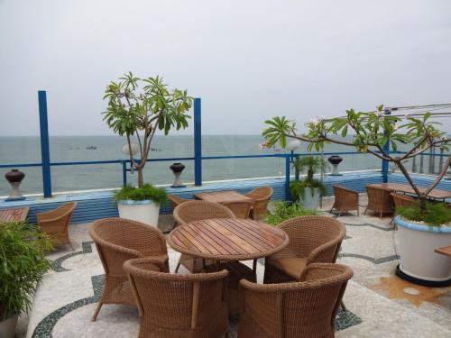 a patio with a table and chairs and the ocean at The Promenade in Puducherry