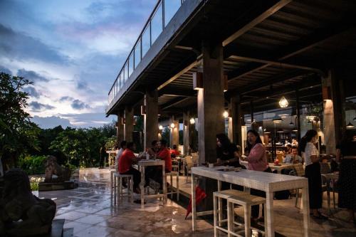 a group of people sitting at tables in a restaurant at Kori Maharani Villas & Resort in Keramas