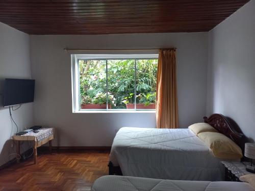 1 dormitorio con 2 camas y ventana en Villa Amada a place to relax and take a rest, en Loja