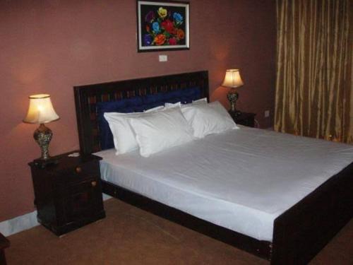 ein Schlafzimmer mit einem großen weißen Bett mit zwei Lampen in der Unterkunft Gulshan Family Couple Guest House Couple Hotel Gulshan-e-iqbal in Karatschi