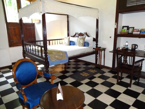 a bedroom with a bed and a table and a chair at Le Dupleix in Puducherry