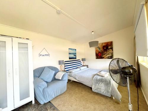 a living room with a couch and a fan at Nautique Beach House - Rustic and Charming, Walk 2 Beach & Shops in Rosebud