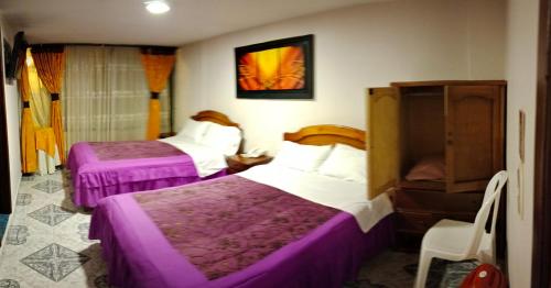 two beds in a hotel room with purple sheets at HOTEL GALERAS in Pasto
