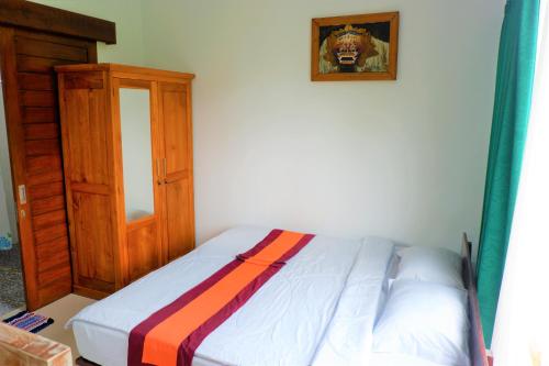 a bed in a room with a wooden cabinet at Karauci Homestay in Abeansemal