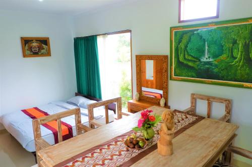 a dining room with a table and a bed at Karauci Homestay in Abeansemal