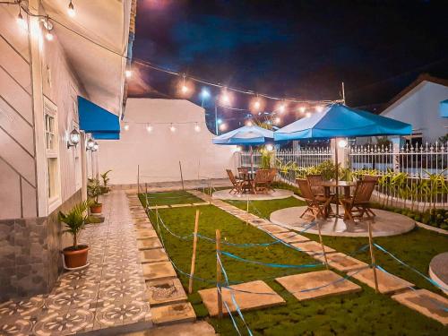 a patio with tables and blue umbrellas at night at Rosemary Homestay in Batu