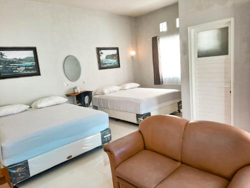 ein Zimmer mit 2 Betten und einem Sofa darin in der Unterkunft Rosemary Homestay in Batu