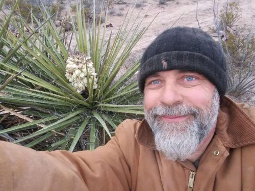 a man wearing a hat standing in front of a plant at Camping at Desert Gardens Oasis in Lobo, TX in Van Horn