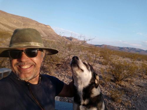 a man in a hat holding a dog with its head up at Camping at Desert Gardens Oasis in Lobo, TX in Van Horn