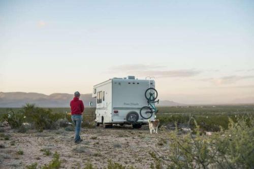 a person standing next to a trailer and a dog at Camping at Desert Gardens Oasis in Lobo, TX in Van Horn