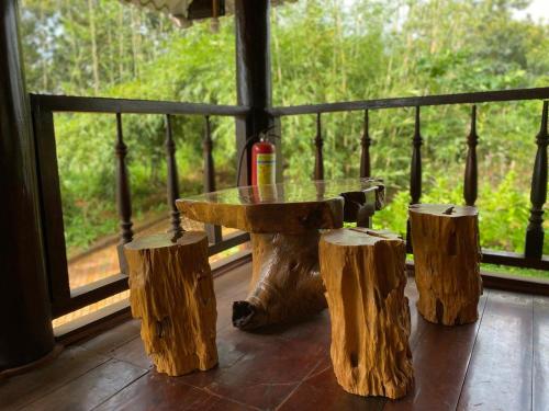 einen Tisch und drei Holzscheite auf einer Veranda in der Unterkunft Phuong Nam Gia Trang Farmstay in Gia Nghĩa