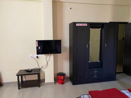 a living room with a tv and a black cabinet at Adheesh Lodge in Dharmastala