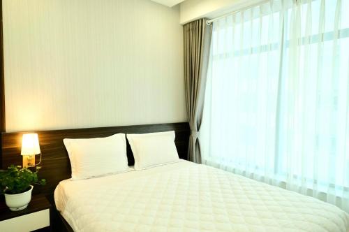 a bedroom with a white bed and a window at Stay in Nha Trang Apartment in Nha Trang