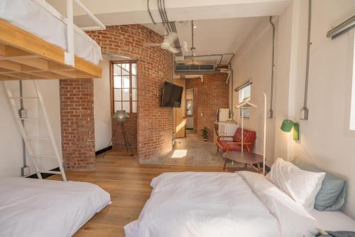 a loft bedroom with two beds and a brick wall at 高雄駁二迴埕Return Trip in Kaohsiung