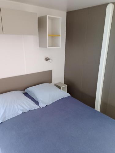 a bedroom with a bed with a blue blanket at Mobil home saint aubin in Saint-Aubin-le-Cauf