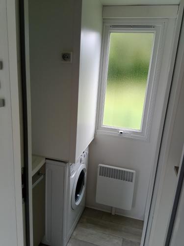 eine Waschküche mit einer Waschmaschine und einem Fenster in der Unterkunft Mobil home saint aubin in Saint-Aubin-le-Cauf