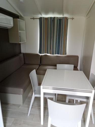 uma pequena sala de estar com uma mesa branca e cadeiras em Mobil home saint aubin em Saint-Aubin-le-Cauf