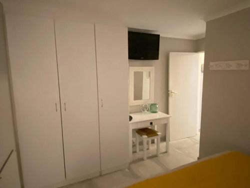 a white bathroom with a sink and a mirror at Huis by die See in Hermanus