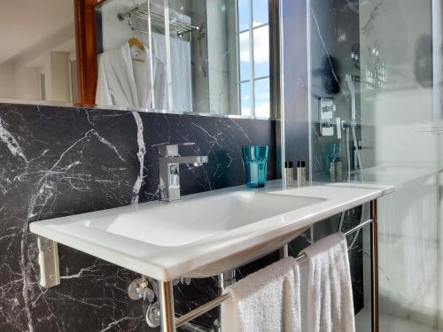 y baño con lavabo blanco y espejo. en Hotel Marqués de Aguilar en Aguilar de Campóo