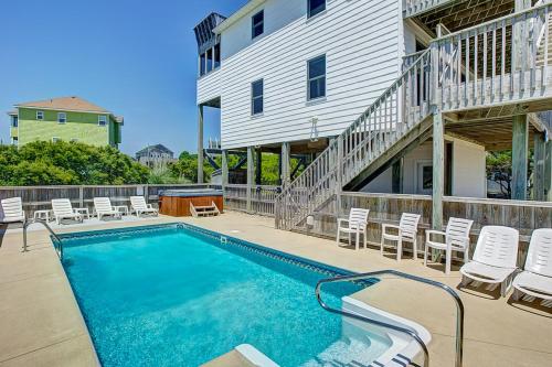 a swimming pool with chairs and a building at Out of the Blue 574 in Rodanthe