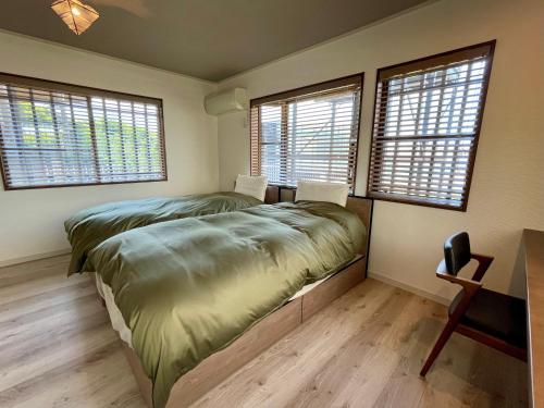 um quarto com uma cama grande num quarto com janelas em Hayama Ocean View Villa -葉山 海を見渡す家- em Hayama