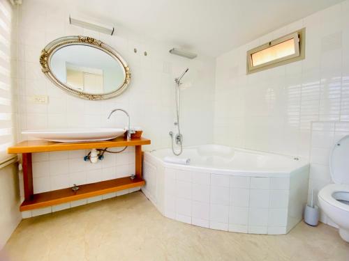 y baño con bañera, aseo y espejo. en White Gordon Beach Apartment, en Tel Aviv
