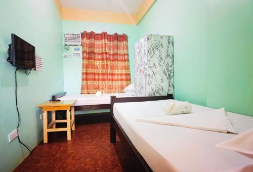 a room with two beds and a television and a window at RedDoorz D128 Lodge Cagayan Valley in Tuguegarao City
