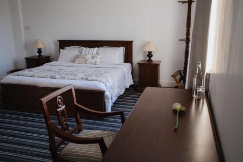 a bedroom with a bed and a table and a chair at Tudor Barn - Little England Cottages in Nuwara Eliya