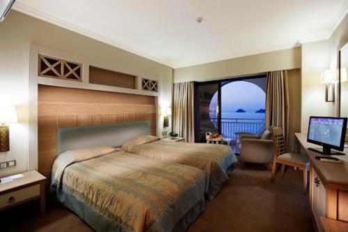 a hotel room with a bed and a desk and a window at Quadas Hotel - Adult Only in Marmaris