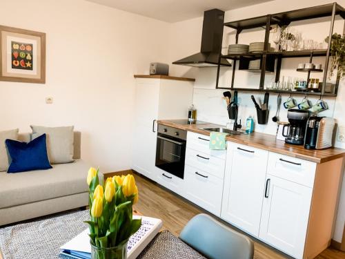 uma cozinha com um sofá e uma mesa com tulipas amarelas em M&M Apartment em Seeg