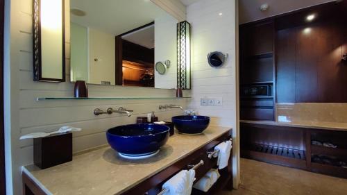 Sanya LUHUITOU Resort & Spa في سانيا: حمام به مغسلتين زرقاء ومرآة