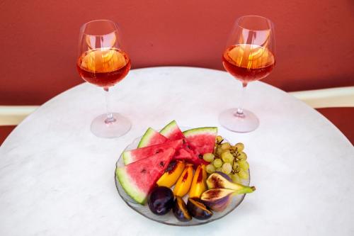 two glasses of wine and a plate of fruit on a table at Marelina Villas in Panormos Rethymno