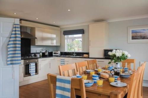 a kitchen with a wooden table with chairs and a dining room at Retallack Resort 4 bedroom lodge - Hot Tub for hire on request -Pool & Spa in Padstow