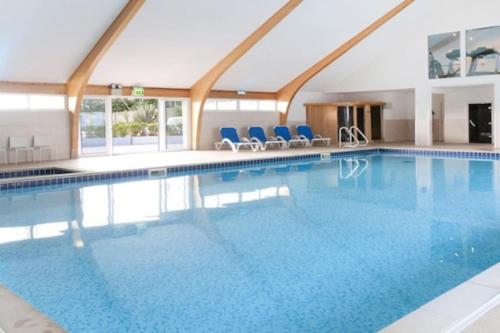 una grande piscina con sedie blu in un edificio di Retallack Resort 4 bedroom lodge - Hot Tub for hire on request -Pool & Spa a Padstow