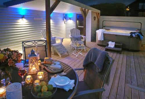 a deck with a hot tub and a table and chairs at SandPipers Luxury hot tub lodge with 2 ensuites a private Sauna & BBQ terrace in Saint Columb Major