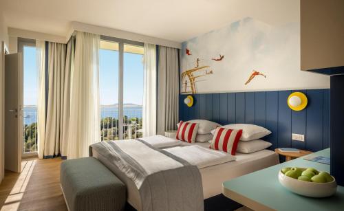 a bedroom with a bed and a table at Falkensteiner Family Hotel Diadora in Zadar