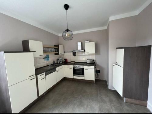 una cocina vacía con armarios blancos y una luz colgante en Ferienwohnung Leonie, en Goslar