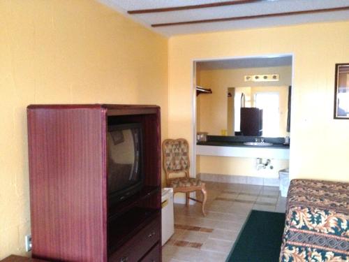 ein Wohnzimmer mit einem TV und ein Zimmer mit einem Sofa in der Unterkunft Holiday Motel in Hugo