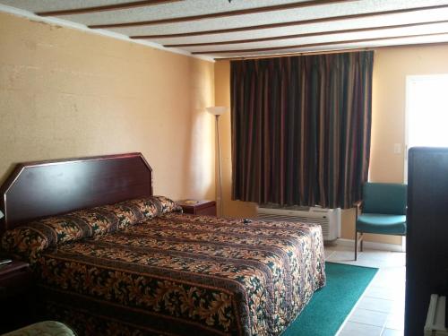 ein Hotelzimmer mit einem Bett und einem Stuhl in der Unterkunft Holiday Motel in Hugo
