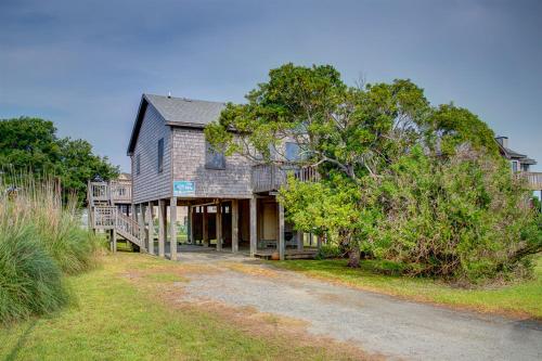 a house with a tree in front of a dirt road at Cape Point 240 in Buxton