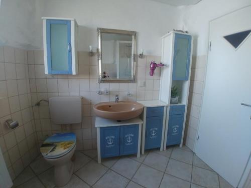a bathroom with a sink and a toilet and a mirror at Ferienwohnung Norddeich in Norden