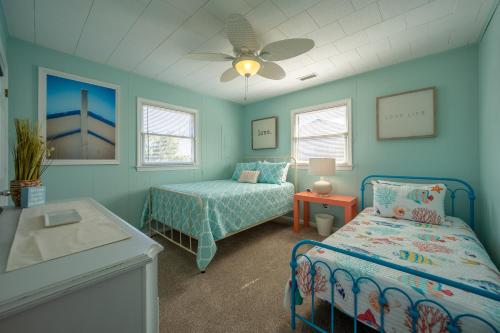 a bedroom with two beds and a table and a ceiling fan at 4 Salty Paws 147 in Avon