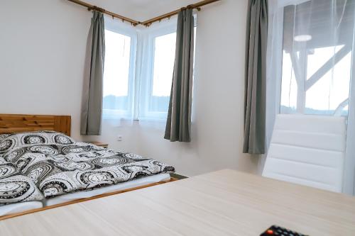 a bedroom with a bed and a large window at Chaty a Apartmány Hracholusky Kemp Kosatka in Pňovany