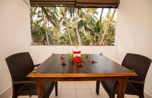 a dining room table with a candle and flowers on it at The Woodside Inn in Benaulim