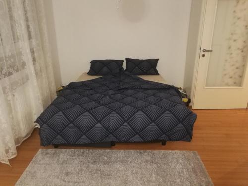 a bed with a black comforter in a bedroom at Iver apartman in Sesvete