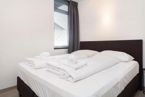 Una cama con toallas blancas encima. en Beneden appartement paviljoenwei 12, Sneek - Offingawier, en Offingawier