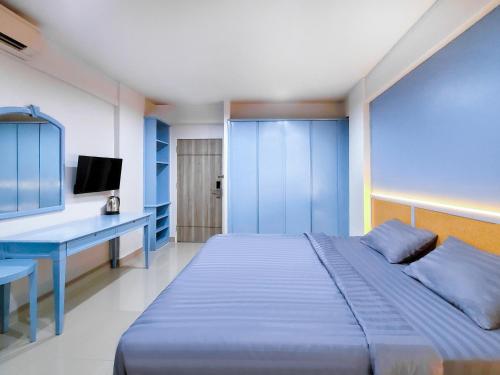 Dormitorio azul con cama y escritorio en Chateau Hotel & Apartments, en Pathum Thani